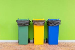 gruppo di cestini colorati sfondo verde, cestini colorati diversi per la raccolta di materiali riciclati. bidoni della spazzatura con sacchi della spazzatura. ambiente e concetto di gestione dei rifiuti. foto