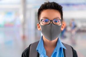 ragazzo in uniforme scolastica che indossa una maschera chirurgica con sfondo sfocato, concetto di protezione dai virus. foto