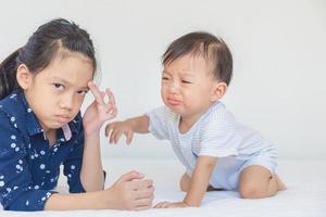 sorella di cattivo umore e fratellino che piange, bambini che giocano sul letto foto