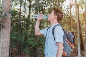 turista maschio che porta un sacchetto di acqua potabile in una bottiglia foto