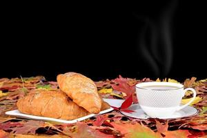 tazza di caffè e colazione e foglie d'acero autunnali sono su un tavolo di legno foto