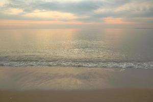 bellissimo sfondo di spiaggia di sabbia con onde morbide sul cielo crepuscolare. foto