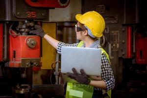 ingegneria industriale e lavoro di squadra che indossano controllo uniforme di sicurezza che opera la rettificatrice del tornio che lavora nella fabbrica industriale. foto