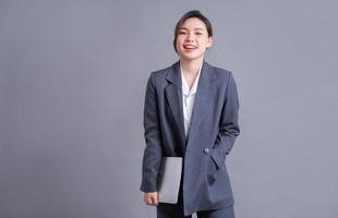 giovane donna asiatica d'affari che indossa un abito e utilizza il laptop su baclground grigio foto