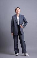 giovane donna asiatica d'affari in piedi su sfondo grigio foto