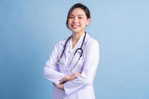 giovane dottoressa asiatica in piedi su sfondo blu foto