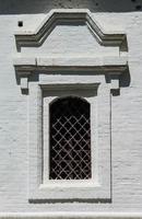 finestrella di antico edificio con grata metallica foto