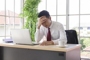 un manager asiatico è stressato in ufficio dopo un forte calo dei ricavi aziendali. foto