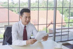 un uomo in un'azienda asiatica riceve documenti importanti sulla sua scrivania con un'espressione scioccata. foto