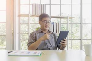 un uomo asiatico di mezza età che usa un iPad in mano. foto