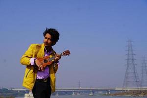 il giovane bell'uomo indiano suona l'ukulele foto