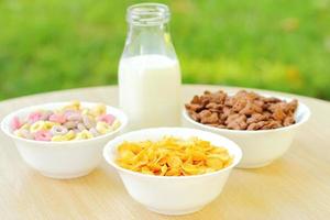 ciotole con diversi tipi di prodotti a base di cereali per la colazione, ciotole bianche con il pasto mattutino foto