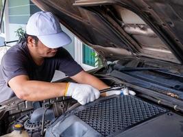 meccanico che tiene in mano una chiave inglese durante la riparazione di un'auto. foto