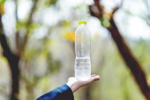 concetto creativo dell'acqua potabile della bottiglia d'acqua e della mano con lo spazio della copia foto