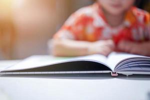 ragazza asiatica ragazzo concentrato leggere un libro, primo piano al libro. con bagliore di luce. foto