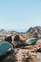 vista panoramica dalla cima dell'isola di padar a labuan bajo con turisti che camminano giù per la collina foto