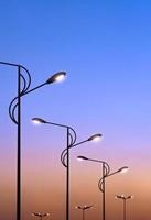 fila di silhouette di lampioni stradali moderni su sfondo colorato cielo drammatico in vista ad angolo basso e cornice verticale foto