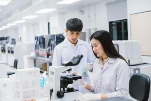 due scienziati medici che lavorano in laboratorio medico, giovane scienziata che guarda al microscopio. selezionare il focus in una giovane scienziata foto