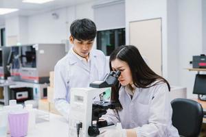 due scienziati medici che lavorano in laboratorio medico, giovane scienziata che guarda al microscopio. selezionare il focus in una giovane scienziata foto