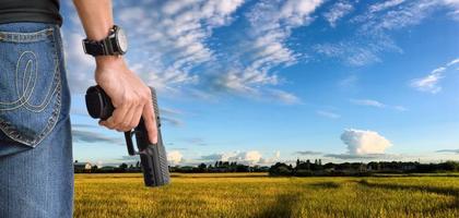 Pistola automatica da 9 mm che tiene nella mano destra del tiratore, concetto di sicurezza, rapina, gangster, guardia del corpo in tutto il mondo. messa a fuoco selettiva sulla pistola. foto