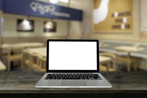 laptop, computer portatile con schermo vuoto su legno nero con sfondo sfocato nel ristorante, tonalità di luce calda. foto
