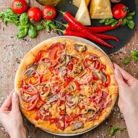 le mani della donna prendono la pizza su un piatto, vista dall'alto foto