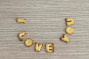ti amo frase disposta con biscotti abc su sfondo di legno di quercia bianca per San Valentino. foto