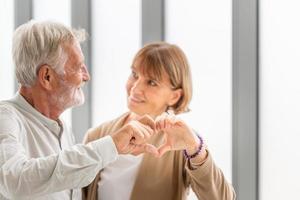 gioiosa bella coppia di anziani che mostra la forma del cuore delle mani, ritratto di felice coppia di anziani mostra il segno del cuore della mano, concetti di coppia di anziani foto