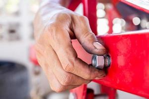 primo piano delle mani del meccanico di riparazione installare bulloni e dadi delle tubazioni, la mano del lavoratore stringe il dado sul bullone foto