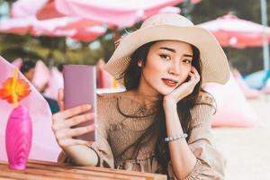 la bella donna asiatica usa lo smartphone si rilassa alla spiaggia di pattaya foto