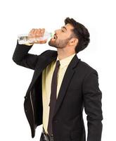 ritratto di giovane uomo che beve acqua dalla bottiglia isolata su sfondo bianco. foto