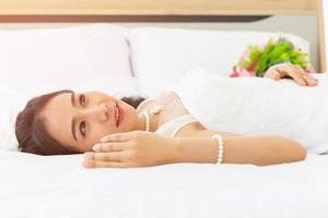 una sposa asiatica indossava un abito da sposa bianco a letto nella stanza. foto