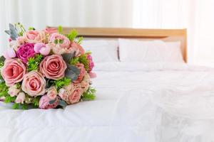 un bel mazzo di fiori era adagiato su un letto bianco e pulito. accanto all'abito da sposa sono stati messi insieme. foto