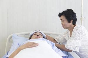una madre asiatica si prende cura della figlia malata su un letto d'ospedale. foto