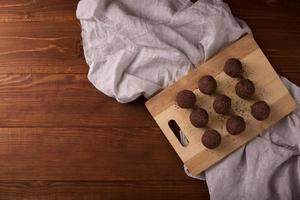 palline di cacao, torte al tartufo di cioccolato a bordo su fondo di legno foto