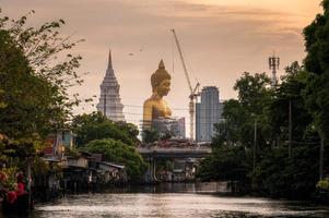 grande buddha dorato con pagoda nella comunità tradizionale sulla riva del fiume a bangkok foto