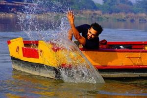 l'uomo si diverte con l'acqua seduto nella barca foto