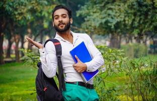 mostrando qualcosa usando la mano immagini di ragazzo indiano studente di college indiano foto