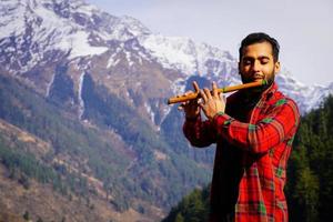 strumento indiano bansuri giovane ragazzo che suona il flauto indiano bansuri in montagna foto