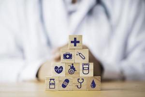 medico che mette e impila il cubo di blocchi di legno che stampa lo schermo sanitario e le icone mediche per il concetto di salute e benessere. foto