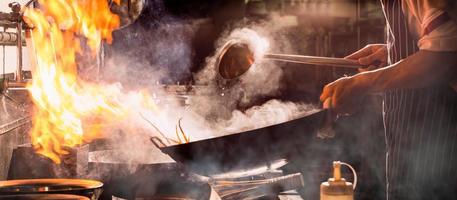 lo chef salta in padella impegnato a cucinare in cucina. foto