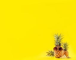 ananas creativo che osserva in su con occhiali da sole e guscio isolato su sfondo giallo, modello di progettazione idea spiaggia vacanza estiva, spazio copia primo piano foto