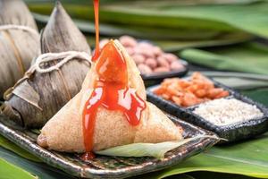 zongzi, gnocchi di riso al vapore con salsa di peperoncino. primo piano, copia spazio, famoso cibo asiatico gustoso nel festival di duanwu della barca del drago foto