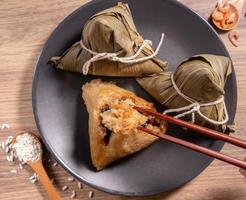 zongzi, donna che mangia gnocchi di riso al vapore su un tavolo di legno, cibo nel concetto di duanwu del festival della barca del drago, primo piano, spazio per la copia, vista dall'alto, disposizione piatta foto