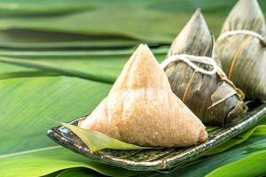 chiudinm up, copia spazio, famoso cibo asiatico gustoso nel festival di dragon boat duan wu, gnocchi di riso al vapore a forma piramidale avvolti da foglie di bambù fatte con ingredienti crudi di riso appiccicoso foto