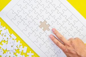 puzzle e le mani sullo sfondo giallo del concetto foto