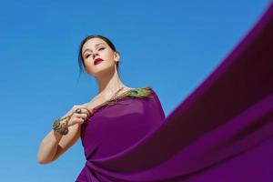 incredibile bella donna bruna con la piuma di pavone in tessuto viola nel deserto. orientale, indiano, moda, concetto di stile foto