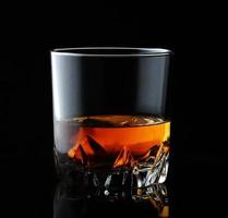 whisky scozzese in un bicchiere elegante su fondo nero con riflessi. foto