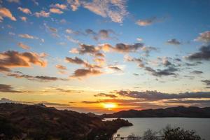 drammatico tramonto sul mare con le colline foto