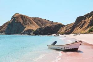 barca vuota sulla spiaggia di sabbia rosa a labuan bajo foto